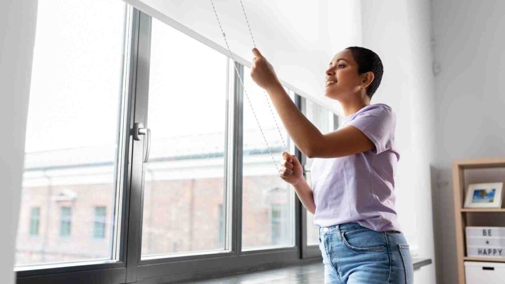 a person is standing in front of a window with a window blind